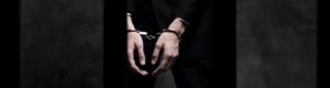 Man handcuffed behind bars